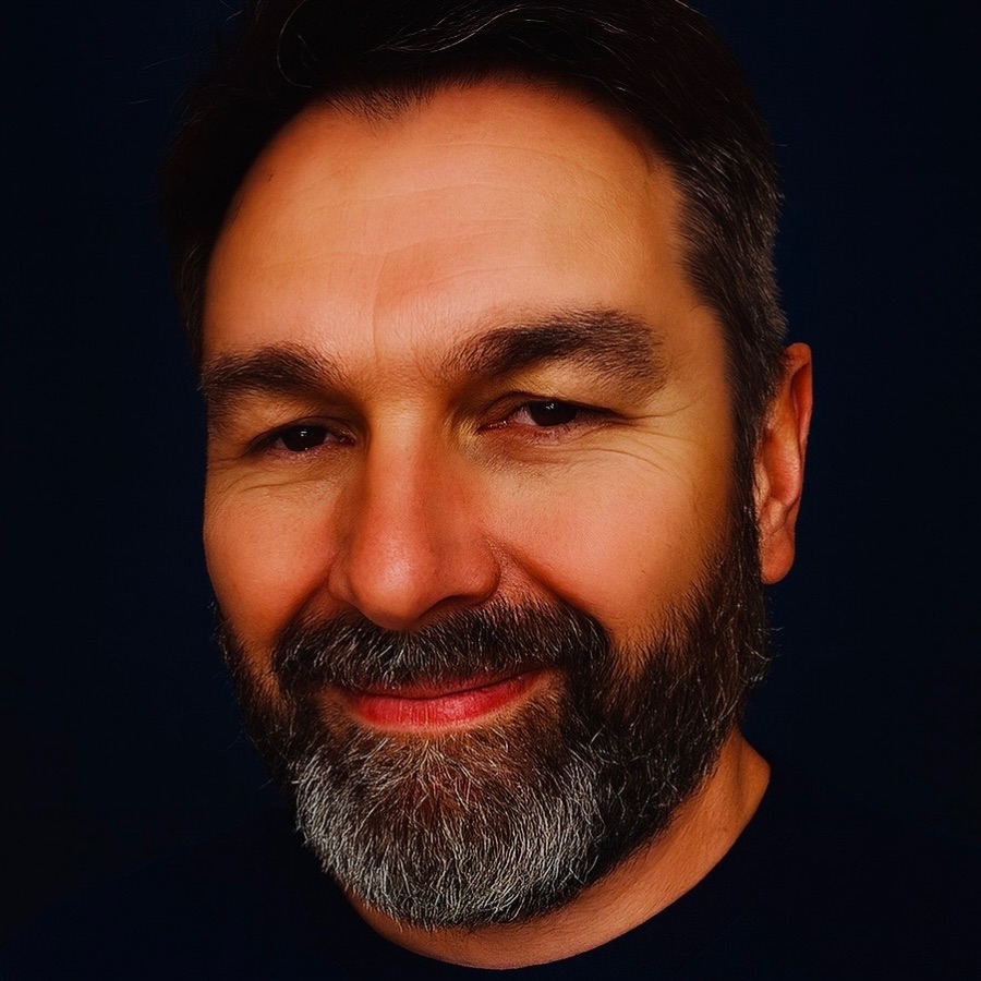 Gary, smiling, photographed against a dark background